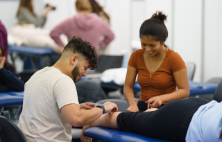 Two graduate students doing hands-on training in the Physical Therapy lab